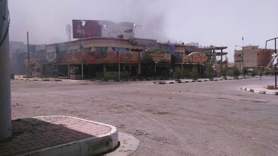 دخان يتصاعد من متاجر في الفلوجة، قال شاهد إن "قوات الحشد الشعبي" أحرقتها في 27 يونيو/حزيران  