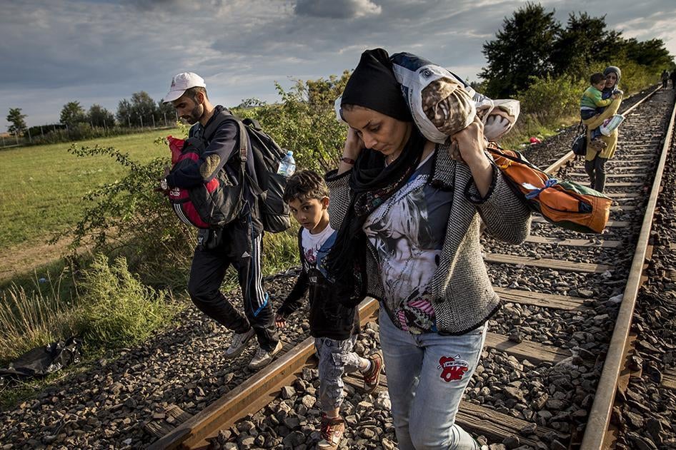 新抵达的难民家庭沿着塞尔维亚的铁路轨道行走，目的地是匈牙利的勒斯凯收容点，从那里他们会被载往临时拘留营。摄于 2015年9月8日。