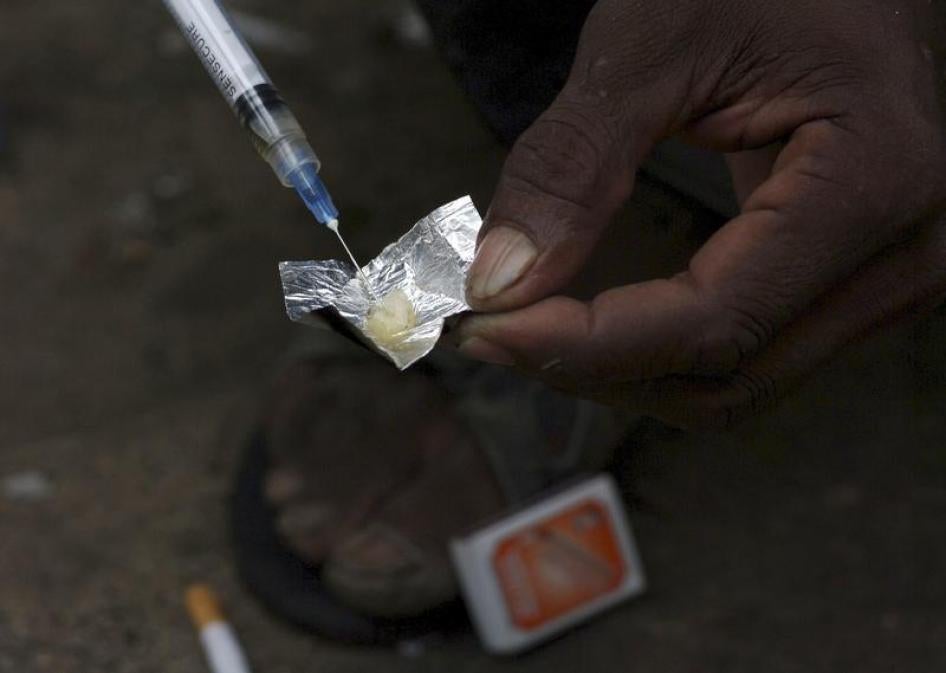 A syringe sucks up a mixture of heroin and water prepared on a foil wrap as addicts shoot up in Stone Town Zanzibar, December 22, 2009.