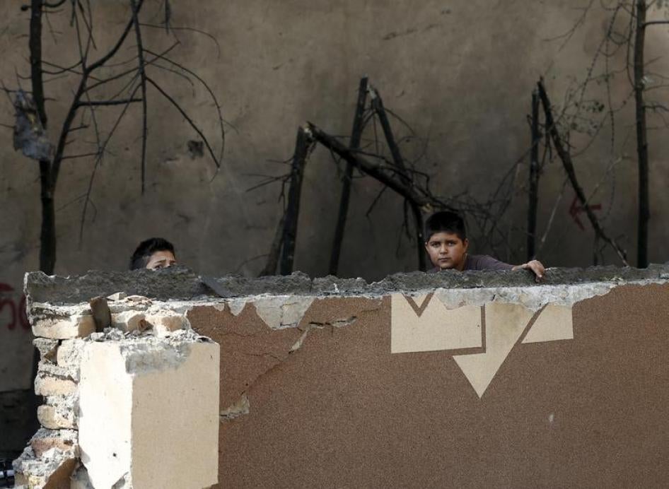 Afghan boys look out from behind a damaged wall after a Taliban attack in Kabul, Afghanistan October 6, 2015.