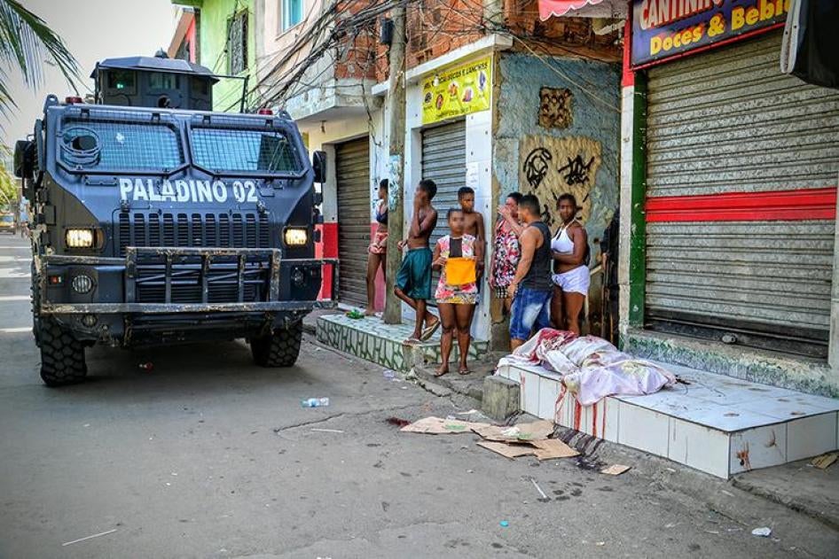 Un vehículo blindado de la policía militar pasa por al lado de una persona asesinada por policías, el 7 de abril de 2016 en la favela de Jacarezinho. La policía militar mató a otras dos personas en la misma redada.