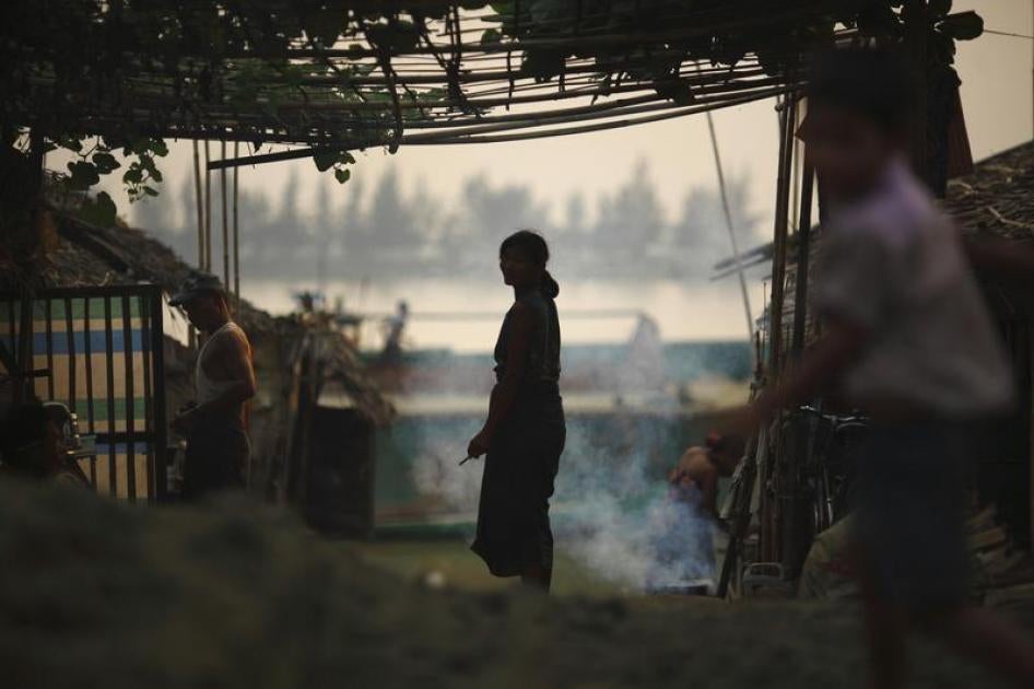 A woman is silhouetted as she stands outside her hut near the bank of Yangon River March 18, 2012.