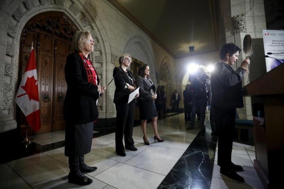 加拿大原住民事务部长卡洛琳・贝内特（Carolyn Bennett）（左）、女性地位部长派翠莎・哈杜（Patricia Hajdu）（左二）和司法部长王州迪（Jody Wilson-Raybould）召开记者会说明调查失踪和遇害原住民女性的计划；记者会开始时，由阿冈昆族（Algonquin）领导人柯萝蒂・孔曼达（Claudette Commanda）（右）带领祷告，2015年12月8日摄于加拿大渥太华。