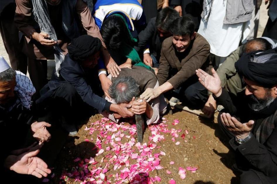 Afghan Shia Muslims men mourn over the grave of a victim who was killed in Tuesday's attack at the Sakhi Shrine in Kabul, Afghanistan October 12, 2016.