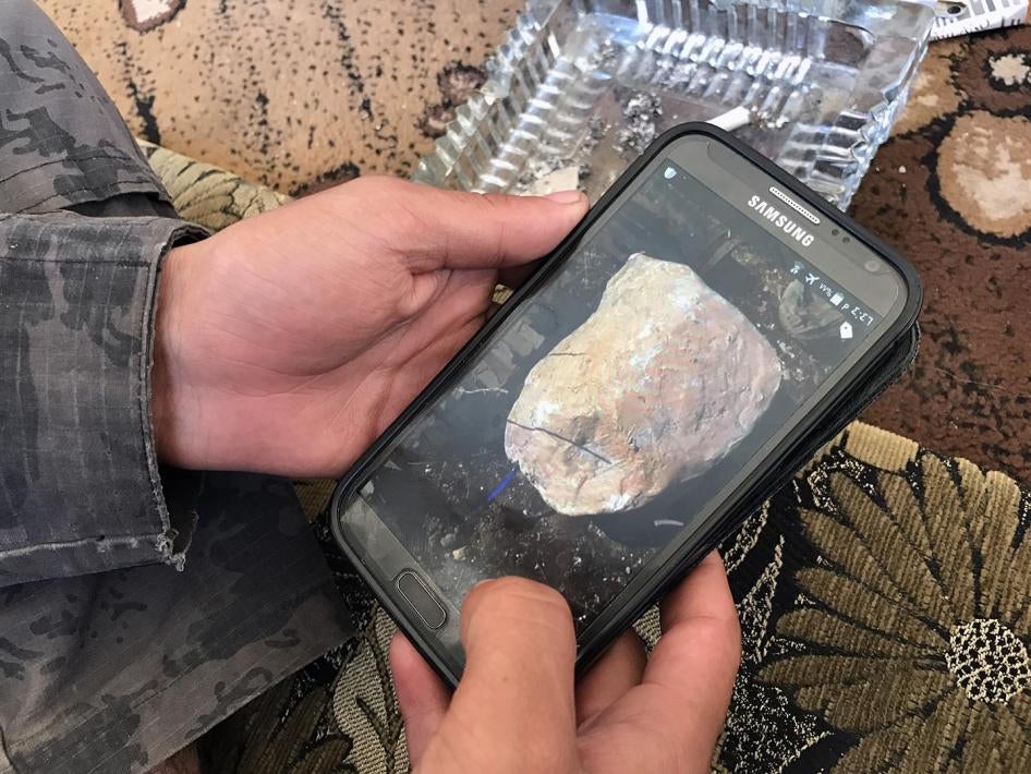 A deminer shows a photograph he took of an improvised explosive device concealed as a rock. 