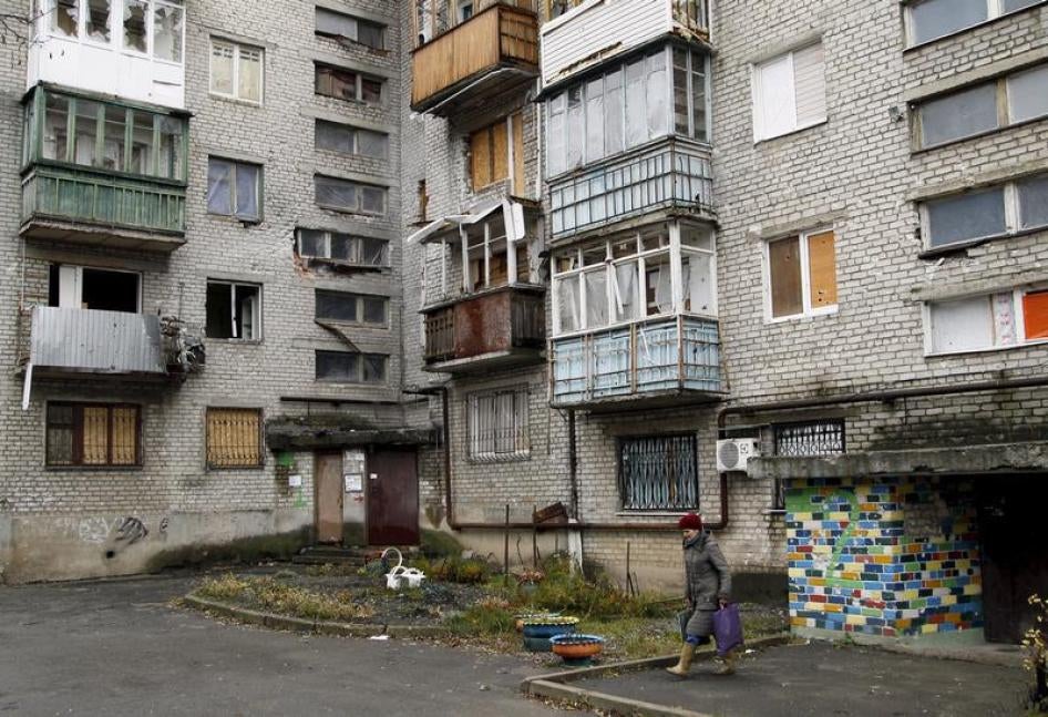 A woman walks out of a residential building that was damaged during battles between Ukrainian armed forces and Russian-backed separatists, in Donetsk, Ukraine November 25, 2015.