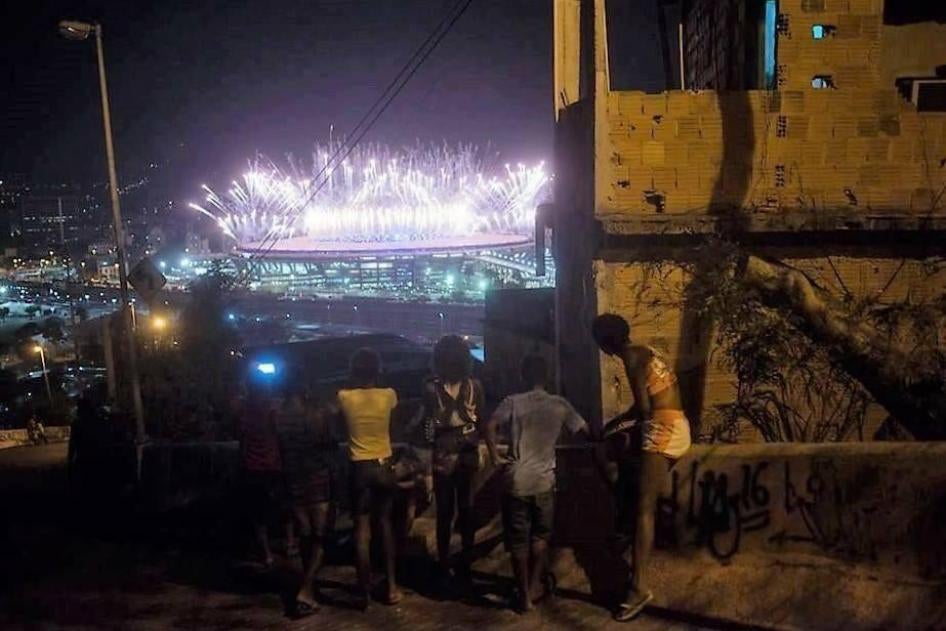 Moradores da favela da Mangueira assistem aos fogos de artifício durante abertura a cerimônia de abertura dos Jogos Olímpicos no estádio do Maracanã, no Rio de Janeiro. 