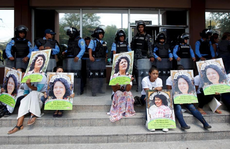Indigenous people hold posters with a photograph of slain environmental rights activist Berta Caceres while sitting in front of riot policemen during a protest to demand justice in Tegucigalpa, Honduras, on March 17, 2016. 