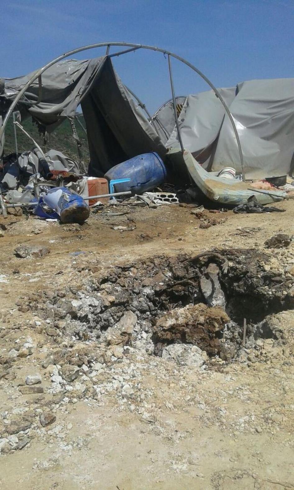 Suriye’nin, Türkiye sınırı yakınlarında yerinden edilmiş kişiler için kurulan Hirmaş  Kampı’nı 15 Nisan 2016’da vuran Suriye hükümet güçlerinin top mermilerinin yarattığı krater ve hasar.