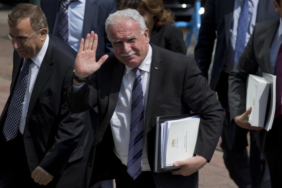 Palestinian Foreign Minister Riyad al-Maliki waves as he arrives holding documents he will submit to the International Criminal Court in The Hague, Netherlands, Thursday, June 25, 2015.