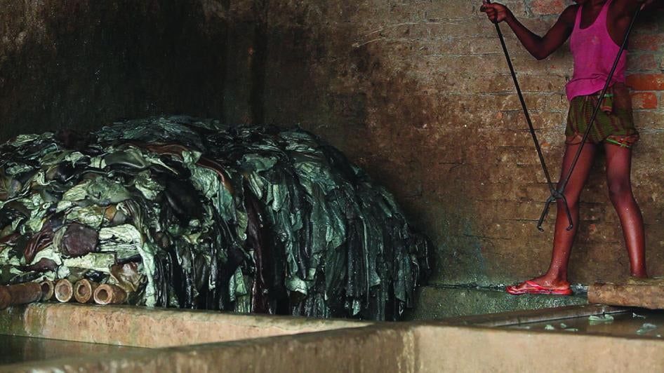 Un garçon se sert de pinces pour tremper des peaux dans une fosse de produits chimiques dilués, dans une tannerie de cuir d'Hazaribagh. 