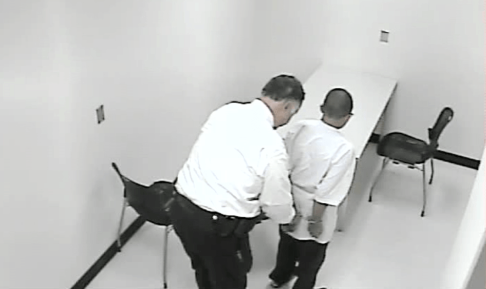 A still from a police interrogation video shows a 13-year-old boy being handcuffed. The pressure of the interrogation caused him to confess to a murder he did not commit. 