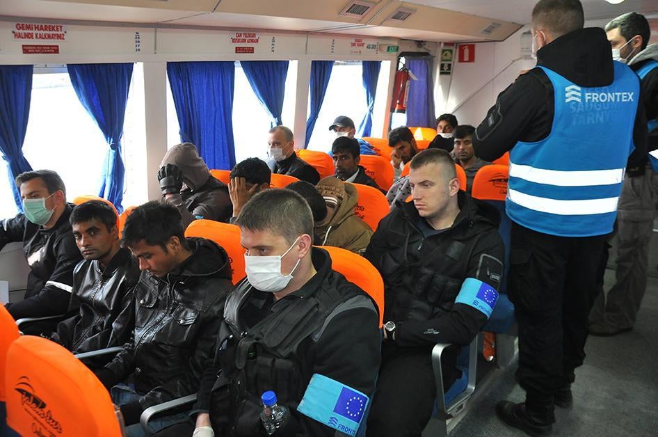 Des migrants assis dans un bateau turc les transportant de l’ile grecque de Lesbos vers Dikili (Turquie), encadrés par des agents de l'agence européenne des frontières Frontex, dont certains portent des masques hygiéniques, le 4 avril 2016.