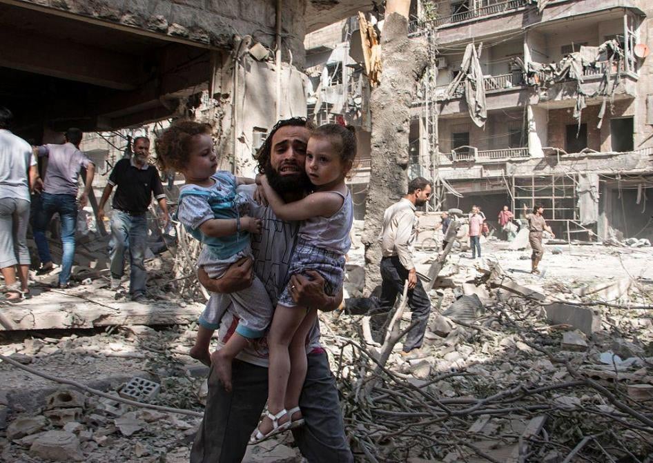 Ein Syrer trägt seine zwei Kinder über Trümmer 