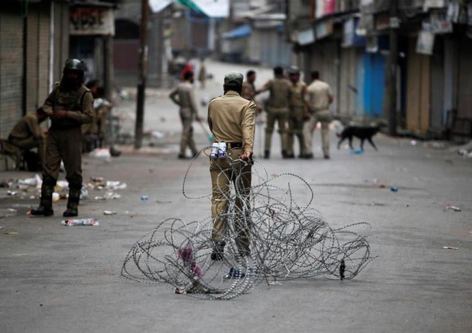 An Indian policeman pulls concertina wire to lay a barricade on a road during a curfew in Srinagar on July 12, 2016. 