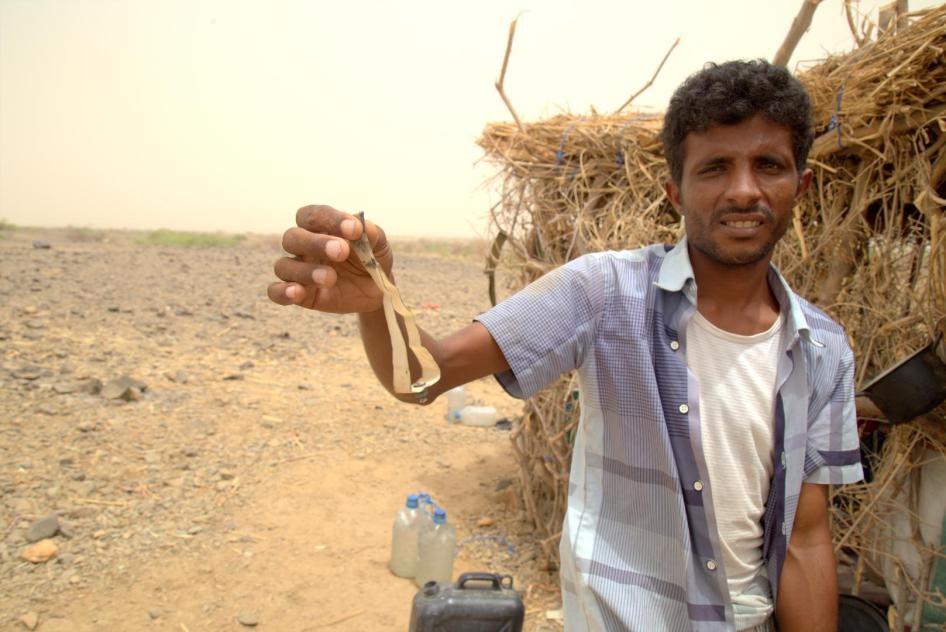 Мужчина держит фрагмент ленты от суббоеприпаса М77. Реактивными снарядами М26 с этими суббоеприпасами было обстреляно селение Малус в Йемене 7 июня 2015 г. 