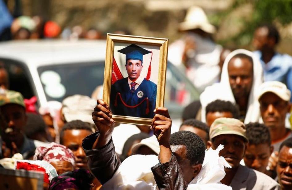 A man at a funeral holds up the portrait of Tesfu Tadese Biru, 32, a construction engineer who died during a stampede after police fired warning shots at an anti-government protest in Bishoftu during Irreecha, the thanksgiving festival of the Oromo people