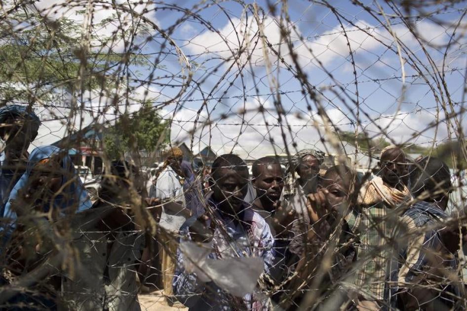 Somali refugees look through a barbed wire fence in Dadaab in 2013.