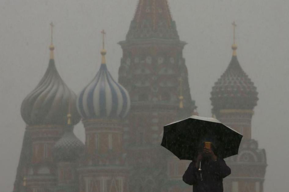 A man walks under an umbrella during a snowfall, with St. Basil's Cathedral seen in the background, in Red Square in central Moscow March 31, 2014.