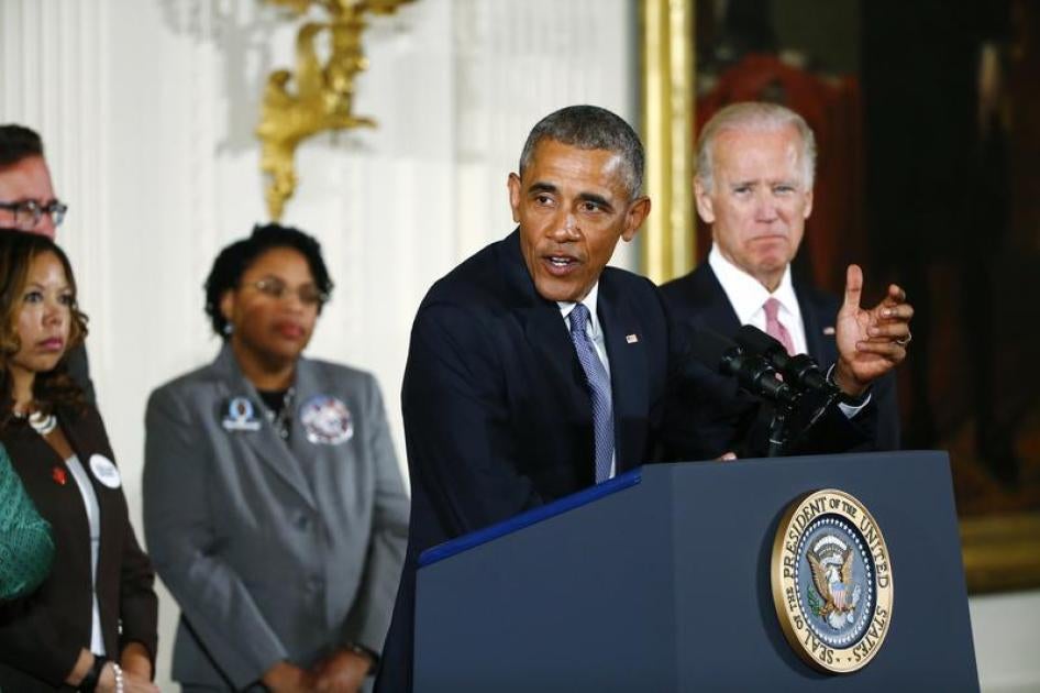 U.S. President Barack Obama stands with Vice President Joe Biden (R) and family members of shooting victims while delivering a statement on steps the administration is taking to reduce gun violence in the East Room of the White House in Washington January
