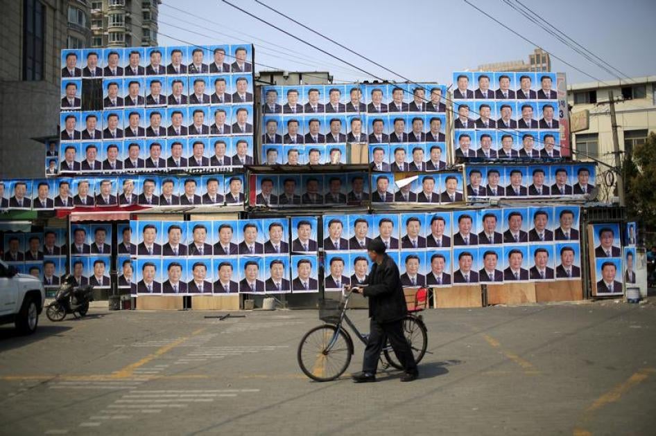 A man with a bicycle walks past a building covered in posters of Chinese President Xi Jinping in Shanghai, China, on March 26, 2016.