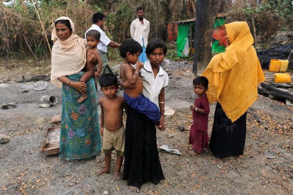 A family stands beside remains of a market which was set on fire, in Rohingya village outside Maungdaw, in Rakhine state, Myanmar on October 27, 2016. 