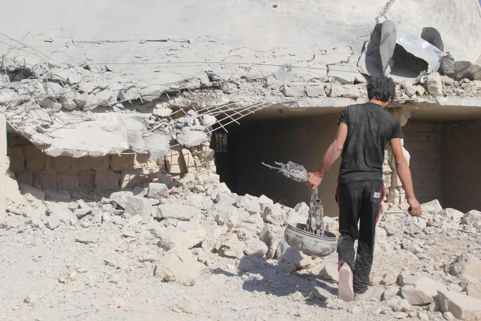 Un homme transporte un fragment de bombe retrouvé parmi les décombres d’une école de la ville de Haas, dans le gouvernorat d’Idlib (nord de la Syrie), suite à des frappes aériennes menées le 26 octobre 2016.