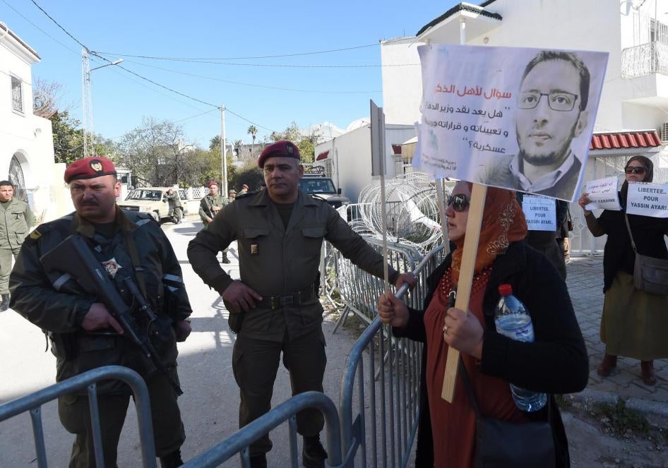 Des membres des forces de l’ordre tunisiennes devant une barrière les séparant de personnes venues manifester leur soutien au blogueur Yassine Ayari lors de son audience d'appel devant un tribunal militaire à Tunis, le 3 mars 2015. 