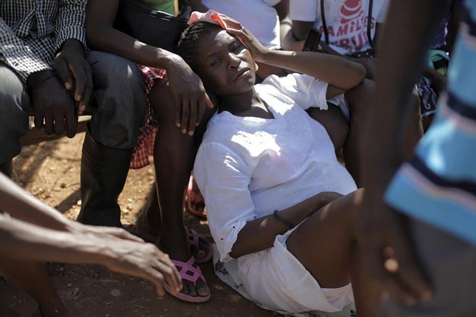 Une femme enceinte se repose par terre lors d'une messe célébrée le dimanche 6 septembre 2015 dans un camp abritant des Haïtiens et Dominicains d'origine haïtienne expulsés de la République dominicaine, situé dans la banlieue d'Anse-à-Pitres dans le sud d