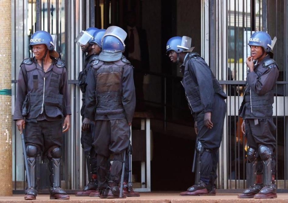 Riot police stand guard as opposition party supporters, arrested following Friday's protest march, arrive at court in Harare, Zimbabwe