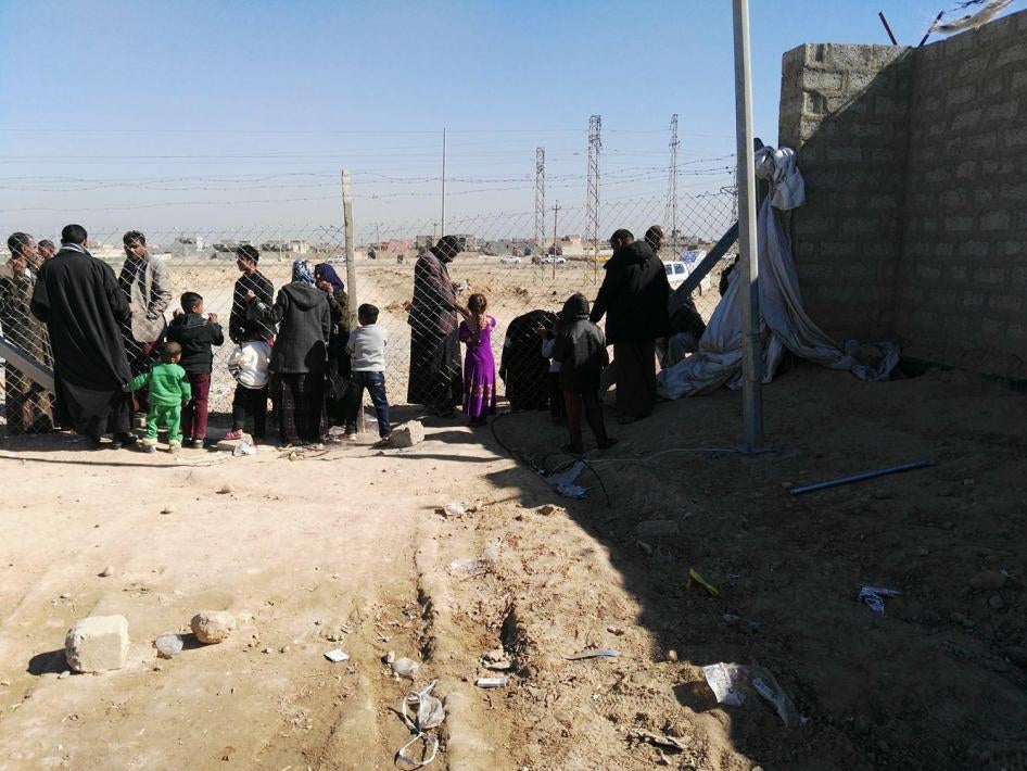 سكان مخيم الشهامة يتكلمون مع أقاربهم من خلال سياج المخيم.