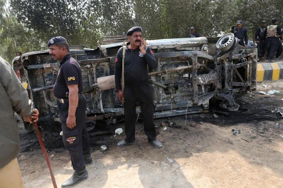 Policemen gather after an angry mob set ablaze a police van along a road in a protest following Thursday's suicide blast at the tomb of Sufi saint Syed Usman Marwandi, also known as the Lal Shahbaz Qalandar shrine, in Sehwan Sharif, Pakistan's southern Si