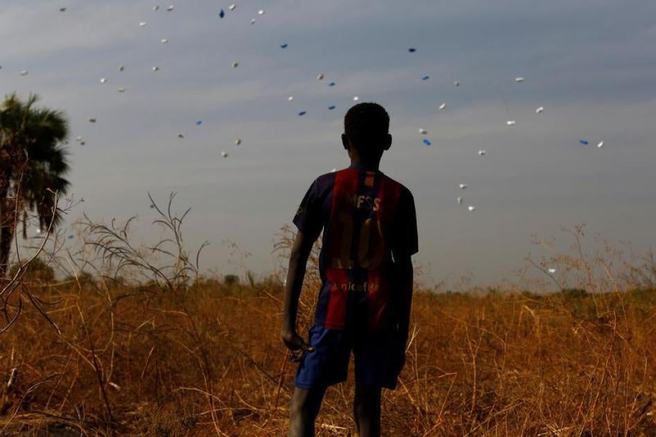 A boy watches sacks of food drop to the ground during a United Nations World Food Programme (WFP) airdrop close to Rubkuai village in Unity State, northern South Sudan, February 18, 2017.