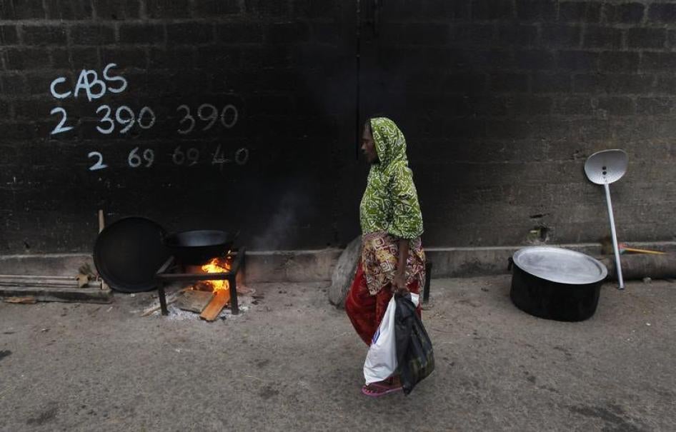 A woman walks past a cooking fire along a road during Eid al-Fitr in Colombo, Sri Lanka, August 8, 2013.