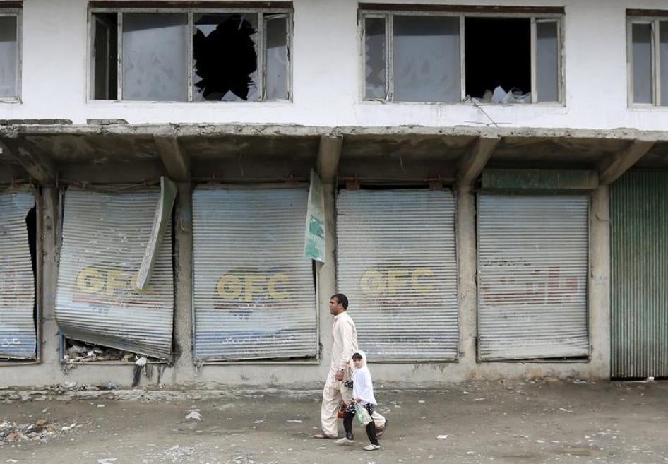 Residents walk past damaged shops after a suicide car bomb attack on a government security building in Kabul, Afghanistan April 19, 2016. 