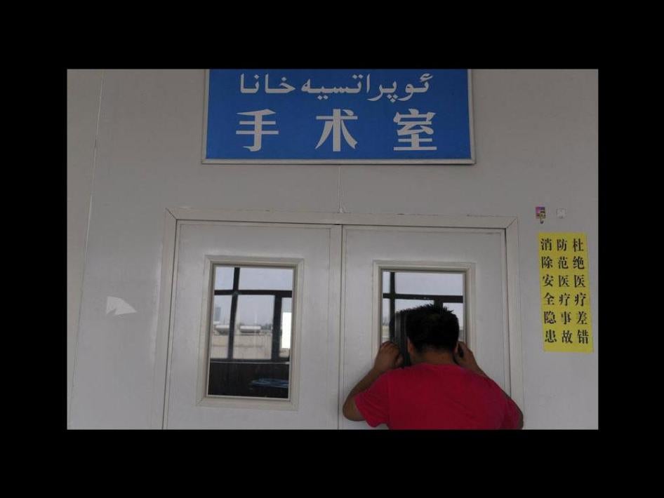 一名男子在医院手术室门外关注进行剖腹生产的妻子，新疆维吾尔自治区沙雅县，2012年6月4日。
