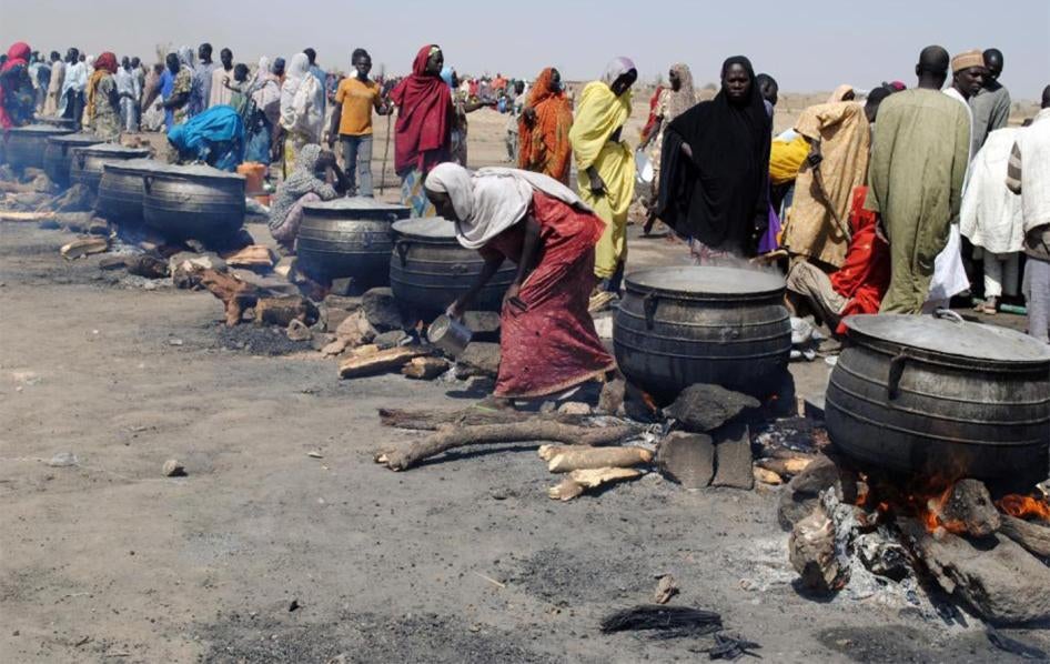 Des femmes réchauffent des aliments dans de grosses marmites dans un camp de personnes déplacées à Dikwa dans l'État de Borno, dans le nord-est du Nigeria, le 2 février 2016.