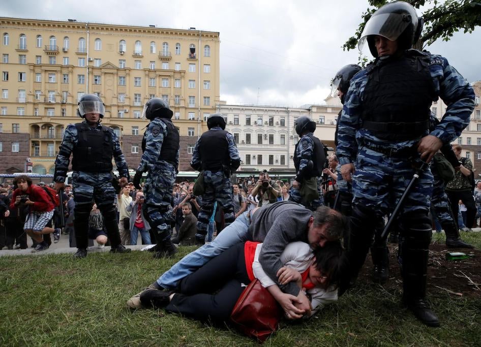 Yulia Galyamina and Nikolai Tuzhilin on the ground with riot police officials next to them. Moscow, July 2017