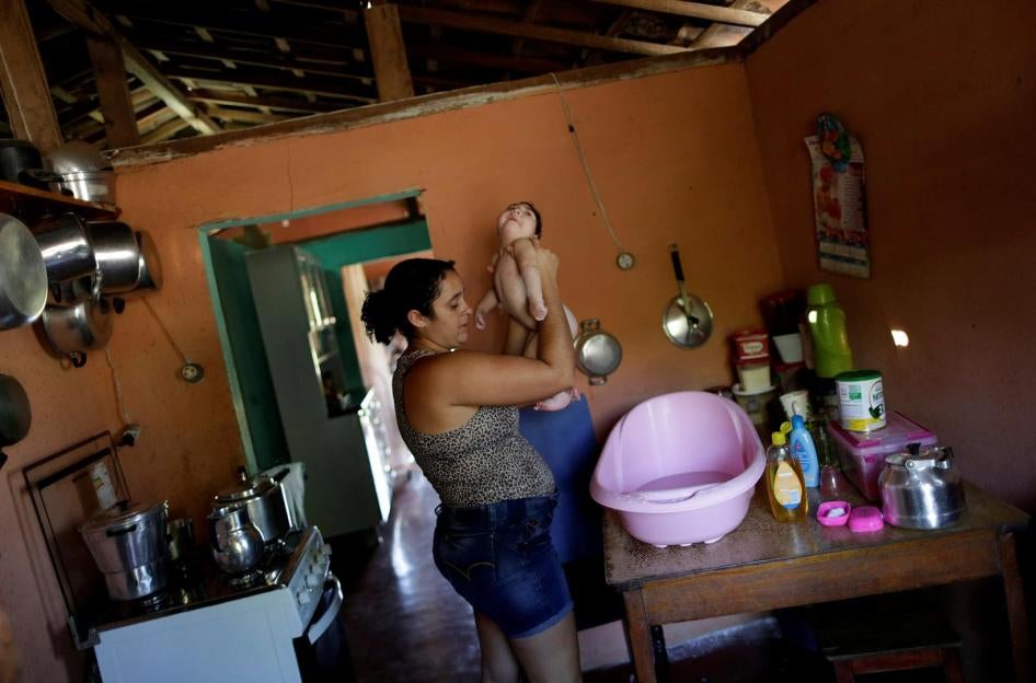Raquel dá banho à sua filha Heloisa, uma menina com síndrome de Zika nascida em abril de 2016. Raquel diz que não pode pagar os medicamentos que suas filhas gêmeas precisam para convulsões.