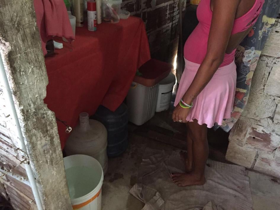 Uma mulher grávida de 25 anos ao lado de recipientes de armazenamento de água descobertos em sua casa em um bairro pobre em Recife, no estado de Pernambuco.