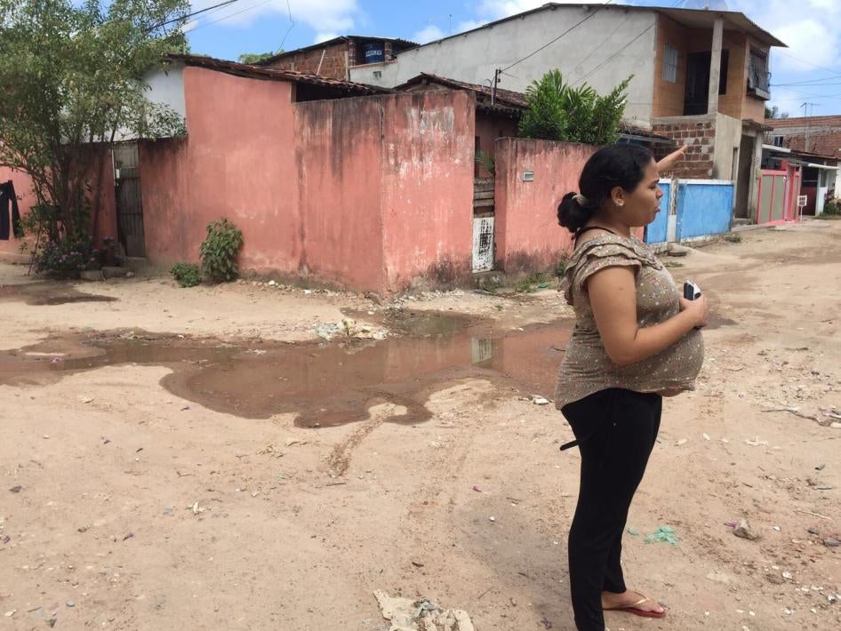 Jéssica, de 24 anos, grávida de oito meses quando conversou com a Human Rights Watch, aponta para a água parada em sua comunidade fora do Recife, no estado de Pernambuco.