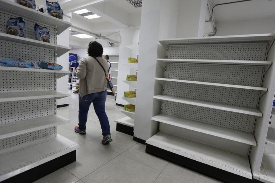 A woman walks past empty shelves at a drugstore in Caracas, February 23, 2016.