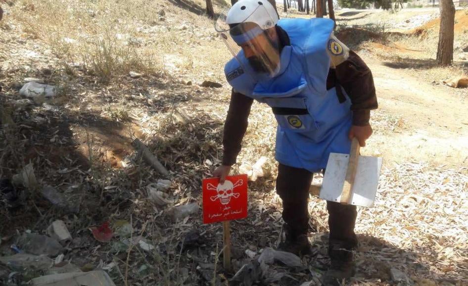 Un technicien faisant partie d’une équipe de « Casques bleus » de la Défense civile syrienne (Syria Civil Defense) pose un écriteau sur le site d’une sous-munition non explosée dans le gouvernorat d'Idlib, en vue d’une future opération de déminage.
