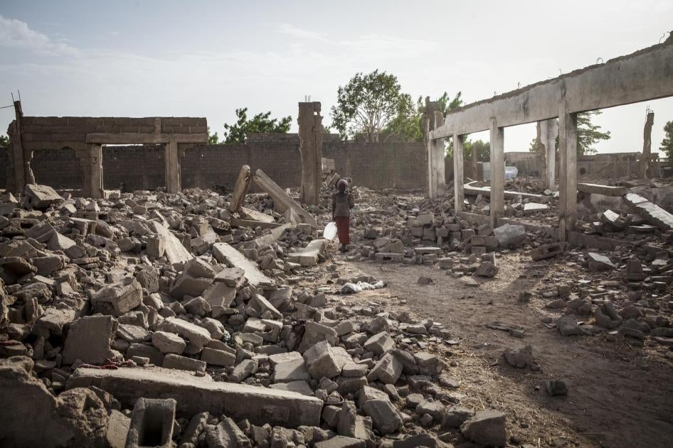 À Banki, dans le nord-est du Nigeria, une jeune fille traverse les décombres de bâtiments détruits, en avril 2017.