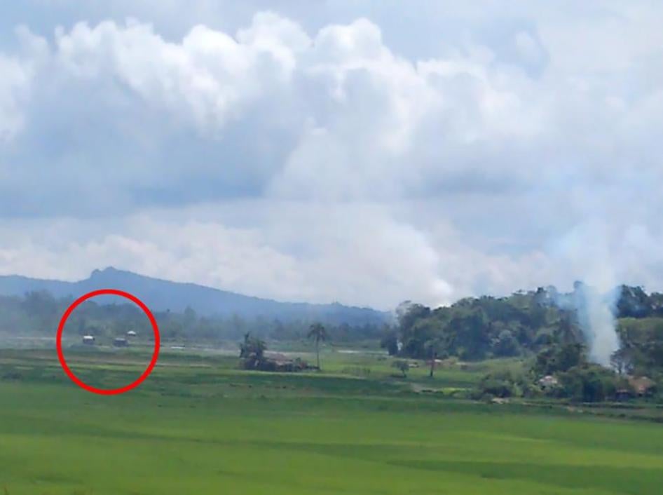 A screen grab of a video shows two dark-colored Burmese military trucks within several hundred meters of a burning village.