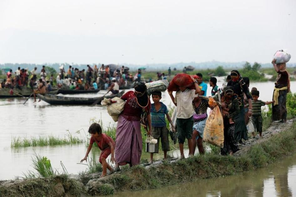  لاجئون من الروهينغا يمشون في طريق موحلة بينما ينتقل آخرون في قارب بعد عبور حدود بنغلاديش مع بورما في تنكاف، بنغلادش، 6 سبتمبر/أيلول 2017. 