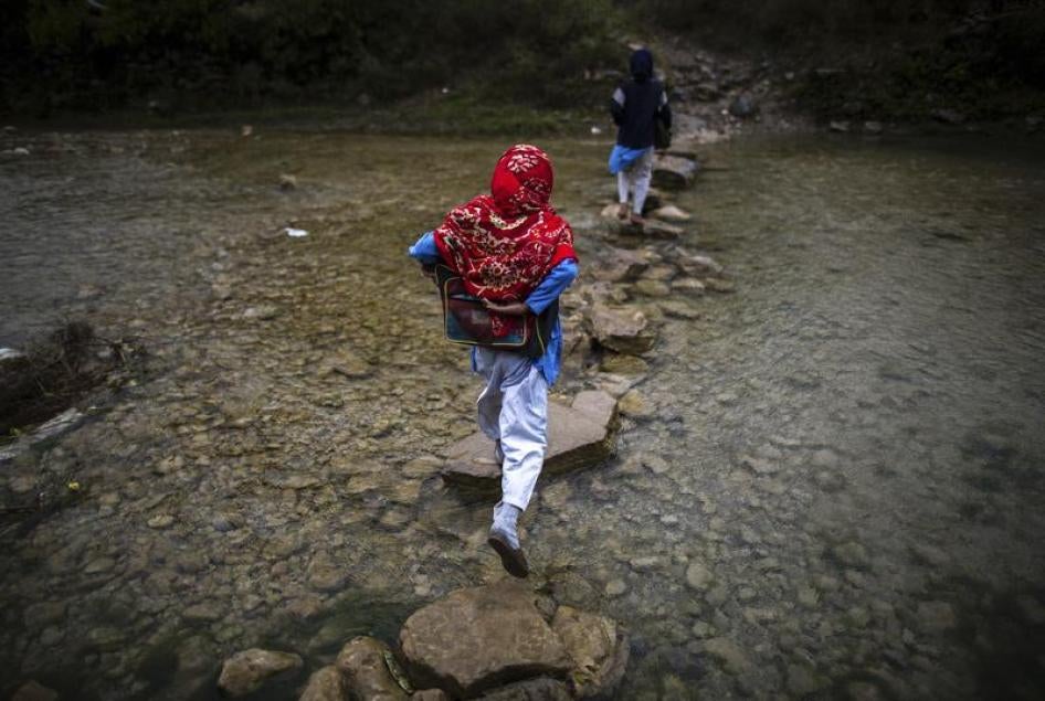 A girl crosses a stream as she walks to school in Margalla Hills, Islamabad, October 24, 2014.