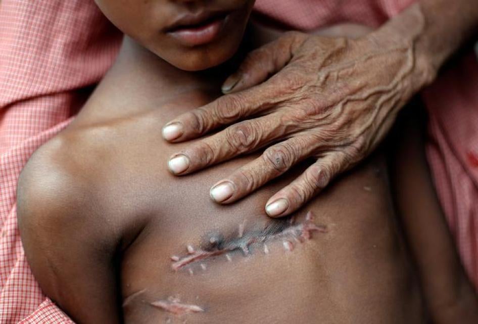 这位年仅七岁的缅甸男童，去年8月跨界逃抵孟加拉前遭枪击胸部。他的父亲，50岁的穆罕默德・塔赫尔（Mohammed Taher）从身后抱著他。摄于孟加拉考克斯巴扎（Cox’s Bazar）附近的库图帕隆（Kutupalong）难民营医疗站，2017年11月5日。