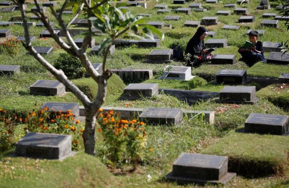 201711Asia_Indonesia_1965 Two people pray at the grave of a loved one in Jakarta, Indonesia, June 26, 2017.