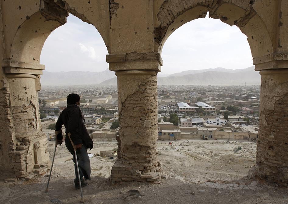 An Afghan child looks over a city while standing with crutches. 